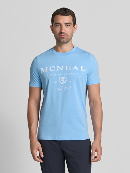 Männermodel trägt T-Shirt mit Label-Print und Rundhalsausschnitt von MCNEAL, Herren T-Shirt aus Reine Baumwolle, Regular-Fit, Ganzkörperansicht von vorne.