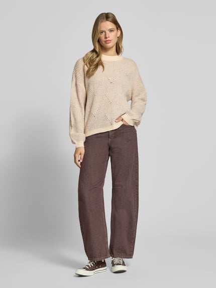 Frauenmodel trägt Pullover mit plastischer Strickstruktur von PIECES, geometrisches Allover-Muster, Strickoptik, Ganzkörperansicht von vorne.