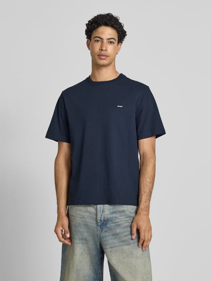 Männermodel trägt T-Shirt mit Label-Patch und Rundhalsausschnitt von REVIEW, dunkles Blau, Baumwolle, Boxy Fit, Ganzkörperansicht von vorne