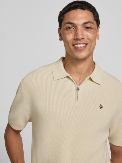 Mannelijk model draagt Boxy Fit Poloshirt met logo-Stitching van REVIEW, puur katoen, boxy fit, polokraag, korte ritssluiting, nahaufnahme bovenlichaam.