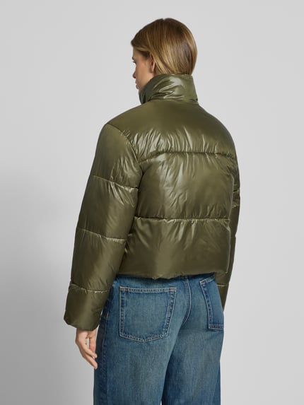 Frauenmodel trägt Puffer Jacket mit glänzender Optik von PIECES in Olivgrün, strukturierte Teilungsnähte, lange Ärmel, Ganzkörperansicht Rückansicht.