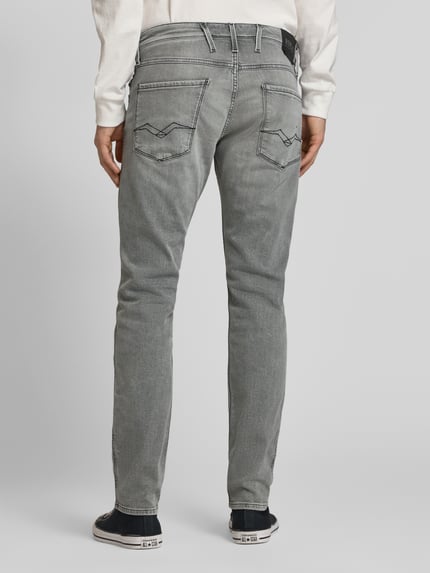 Mężczyzna nosi Slim Fit Jeans mit Eingrifftaschen Modell 'Anbass' von Replay, mieszanka bawełny i elastanu, krój slim fit, wpuszczane kieszenie, szerokość w rozmiarze 32/32: 44 cm, długość wewnętrzna nogawki: 81 cm, szara tekstura, widok całej sylwetki z tyłu.