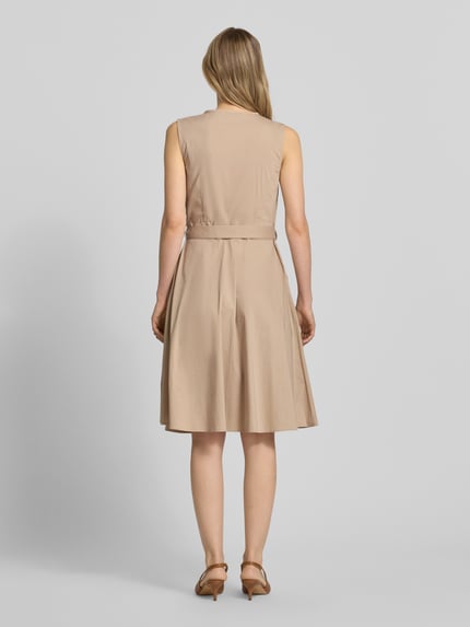 Modelka kobieca nosi Kleid mit V-Ausschnitt in Wickel-Optik von More & More, beżowy, elastyczna mieszanka bawełny, krój slim fit, bez rękawów, odpinany pasek w talii, długość tyłu w rozm. 36: 100 cm, szerokość w rozmiarze 36: 35 cm, widok całej sylwetki z tyłu