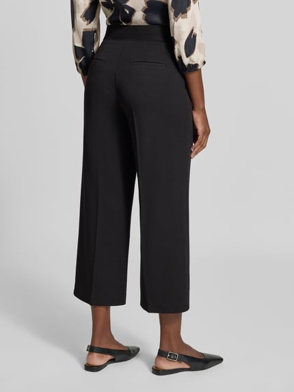 Frauenmodel trägt Regular Fit Weite Hose mit Bügelfalten Modell 'LT JULI' von Betty Barclay in Schwarz, Ganzkörperansicht Rückansicht, Damen Weite Hose von Betty Barclay.