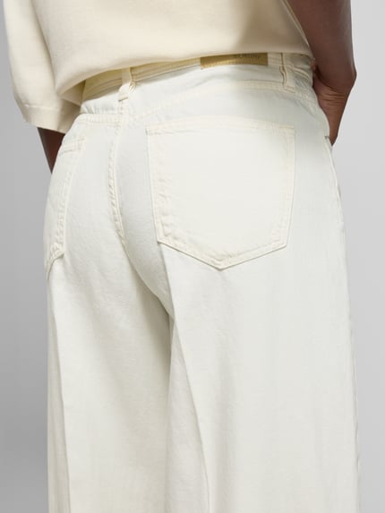 Männermodel trägt Wide Leg Culotte-Jeans aus Baumwoll-Lyocell-Mix von s.Oliver RED LABEL, efekt: jednolity kolor, denim, mieszanka bawełny i lyocellu, wpuszczane kieszenie, z tyłu kieszenie, naszywka z logo, nity, boczne paski, szlufki na pasek, guzik i zamek błyskawiczny, krój wide fit, wysoki stan, długość cropped, kolor ecru, tekstura gładka, Ganzkörperansicht Rückansicht