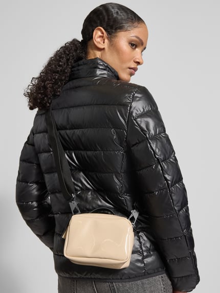 Vrouwenmodel draagt Handtasche met Reißverschluss Modell 'BOX BAG MICRO' van RAINS in beige met labeldetail en verstelbare schouderriem, hoofdzak met rits, afmeting 17x12x8 cm, schouderriem 87 cm, geheellichaamsaanzicht achteraan.