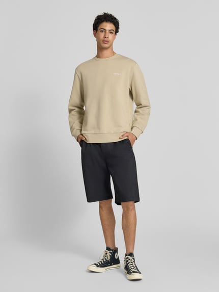 Männermodel trägt beige Sweatshirt mit ronde hals und labelstitching, mix van katoen en elastaan, regular fit, Carhartt Work In Progress, ganzkörperansicht von vorne.