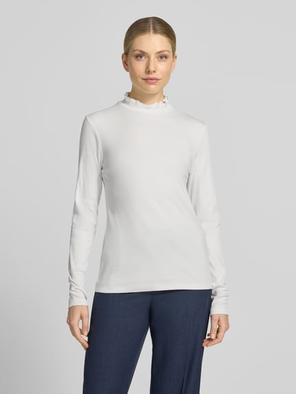 Frauenmodel trägt Slim Fit Longsleeve aus Baumwoll-Mix von MORE & MORE in Weiß mit Stehkragen und Strukturmuster, Ganzkörperansicht von vorne.