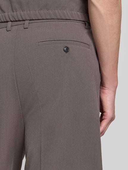 Männermodel trägt Straight Fit Shorts mit Viskose-Anteil von Lindbergh, Elastischer-Material-Mix, Bundfalten, Gesäßtasche, Detailaufnahme.