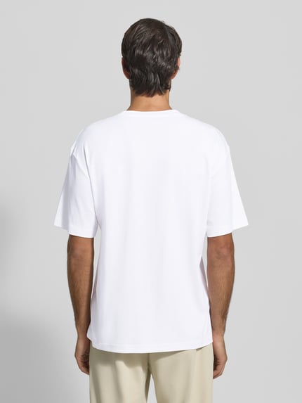 Männermodel trägt Relaxed Fit T-Shirt aus reiner Baumwolle Modell 'JOIN' von BOSS Green in Weiß, glatte Struktur, Ganzkörperansicht Rückansicht.