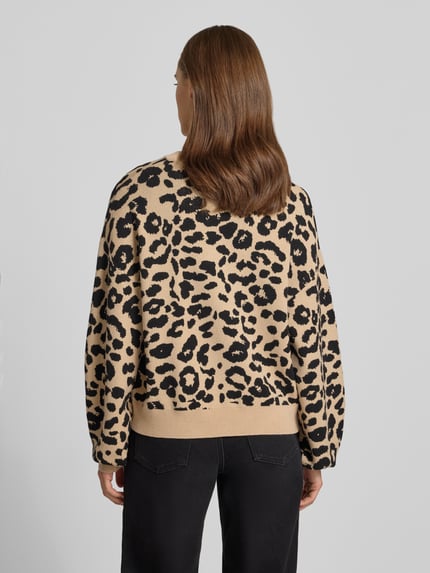 Frauenmodel trägt Relaxed Fit Pullover aus Viskose-Mix Modell 'Charlott' von NOISY MAY® mit Animal-Print, schwarz-beige, gerippte Abschlüsse, Langarm, Rundhalsausschnitt, Ganzkörperansicht Rückansicht.
