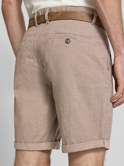 Männermodel trägt Bermudas mit Gürtel und Eingrifftaschen Modell 'NEBRASKA' von Redefined Rebel in Beige, Baumwoll-Mix mit Stretch-Anteil, Ganzkörperansicht Rückansicht, Herren Bermudas, Knopf- und Reißverschluss, Gürtel mit Dornschließe, Französische Eingrifftaschen, Gesäßleistentaschen, Bundweite bei Größe L 46 cm, Innenbeinlänge bei Größe L 21 cm.