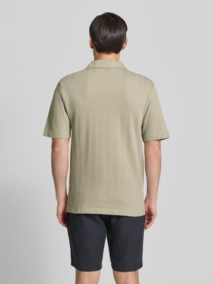 Männermodel trägt Relaxed Fit Poloshirt mit Strukturmuster Modell 'DALIBO' von HUGO, Optik: Unifarben, reine Baumwolle, Ganzkörperansicht Rückansicht.