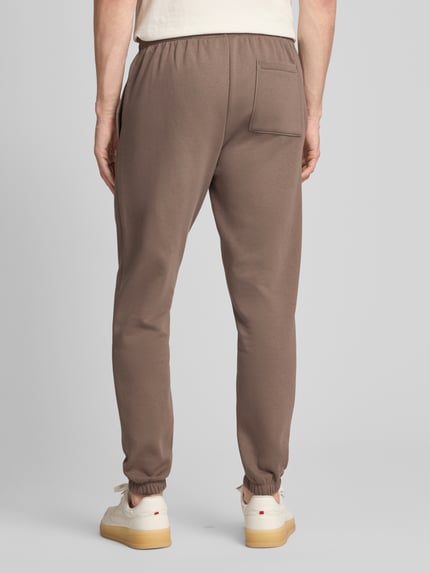 Männermodel trägt Sweatpants mit Eingrifftaschen von GAP aus Baumwoll-Mix, Regular-Fit, Logo, braun, Ganzkörperansicht Rückansicht.