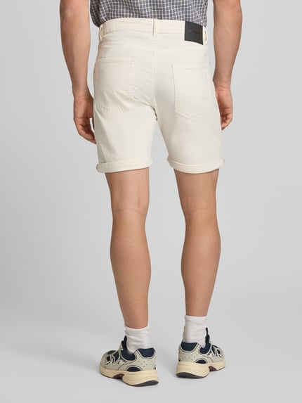 Männermodel trägt Jeansshorts mit Umschlag und Eingrifftaschen Modell 'RICK ALLEN' von Jack & Jones aus Baumwoll-Elasthan-Mix, Regular-Fit, Farbe Creme, strukturierte Oberfläche, Bundweite Größe M 43 cm, Innenbeinlänge 20 cm, Ganzkörperansicht Rückansicht.