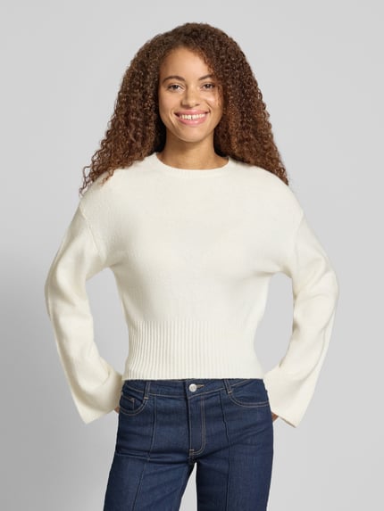 Frauenmodel trägt Pullover mit ausgestelltem Ärmelabschluss von ONLY, unifarben, cropped, Strick, Rundhals, gerippt, Ganzkörperansicht von vorne