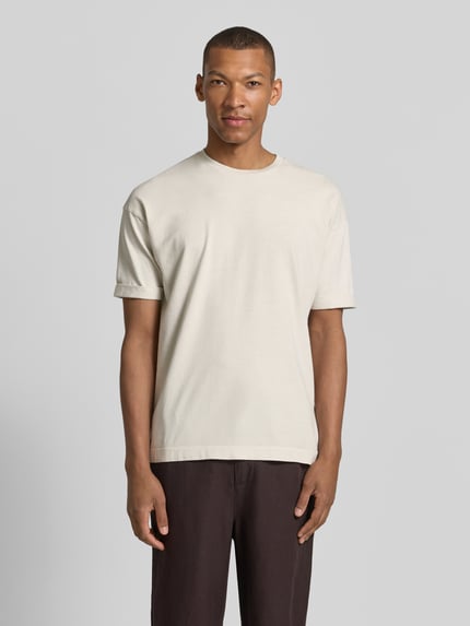 Männermodel trägt T-Shirt mit Ärmelaufschlag und Rundhalsausschnitt von Drykorn, Reine Baumwolle, Regular-Fit, Rückenlänge 70 cm, Ganzkörperansicht von vorne.