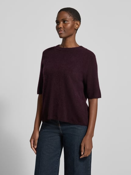 Frauenmodel trägt Relaxed Fit Strickpullover aus reiner Wolle von COMMA in dunklem Beere, feine Textur, 1/2-Arm, Ganzkörperansicht von vorne. Modell 'SEPTEMBER & OKTOBER', Rückenlänge 54 cm, Ärmellänge 30 cm.