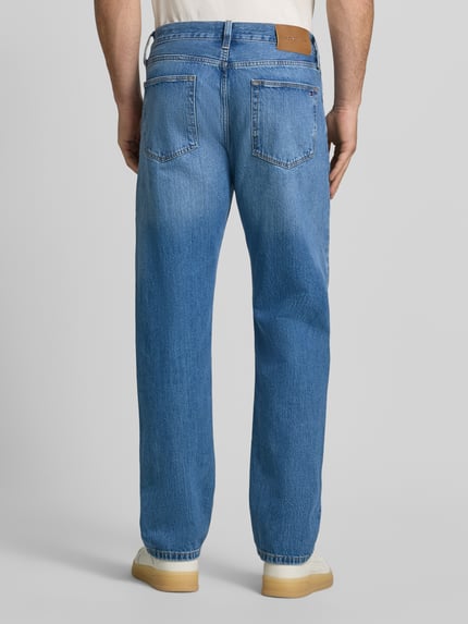 Männermodel trägt Straight Fit Jeans aus von Tommy Hilfiger in klassischem Blau, strukturierte Denim-Textur, Ganzkörperansicht Rückansicht. Herren Straight Fit Jeans von Tommy Hilfiger.