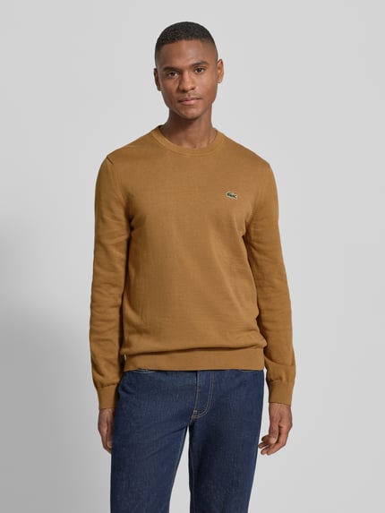 Männermodel trägt Regular Fit Strickpullover aus Baumwoll-Mix von Lacoste, Optik: Unifarben, Label-Patch, Rundhals, Ganzkörperansicht von vorne.
