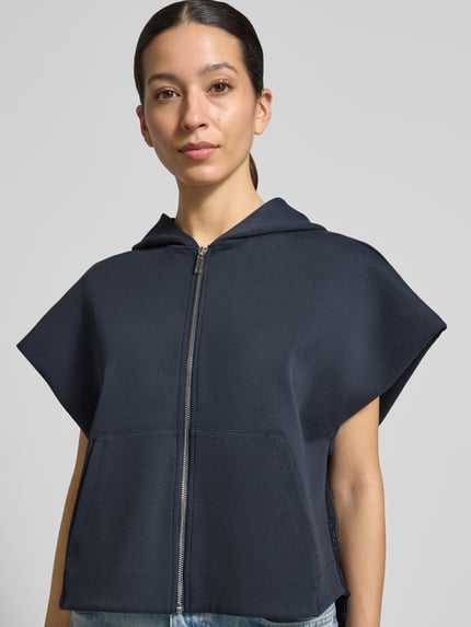 Vrouwenmodel draagt Loose Fit Sweatjacke aus Baumwoll-Mix Modell 'GATTINI' van MAX&Co., effen donkerblauw, katoenmix met capuchon, kangoeroezak en labelopdruk, zijkant stretch inzetstukken, sweatmateriaal, vooraanzicht bovenlichaam close-up.