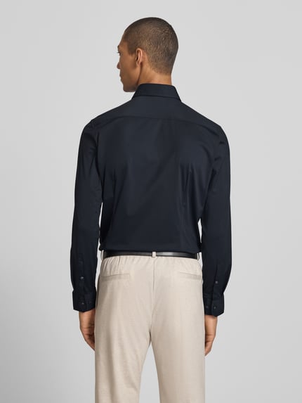 Männermodel trägt Slim Fit Business-Hemd mit Haifischkragen von SEIDENSTICKER, Material-Mix mit Stretch-Anteil, Ganzkörperansicht Rückansicht.