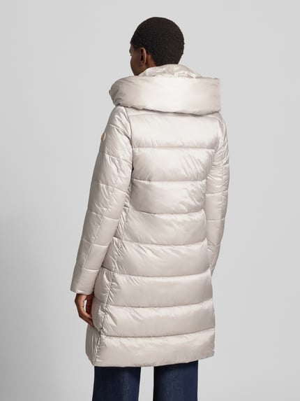 Frauenmodel trägt Steppmantel mit Kapuze Modell 'LYSA' von Save The Duck in hellem Beige, gesteppte Struktur, gerader Schnitt, Rückenansicht.