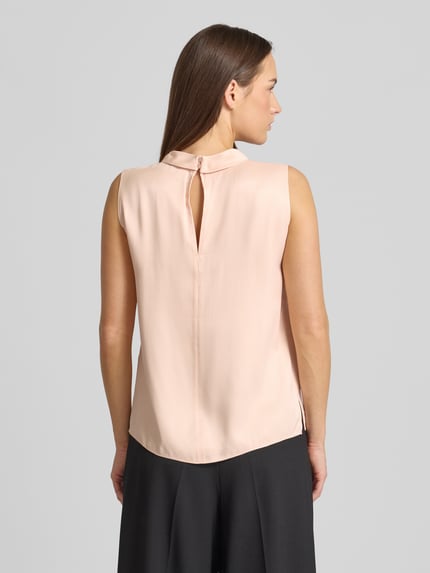 Vrouwenmodel draagt Regular Fit Blusentop uit pure viscose model 'BAURINA' van BOSS in effen lichtroze, satijntextuur, rugsluiting met knoop, detailopname rugaanzicht.