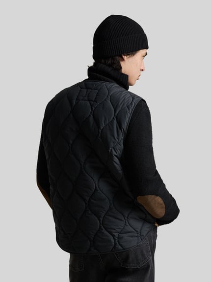 Männermodel trägt Regular Fit Steppweste mit Brusttasche von Polo Ralph Lauren in Schwarz, gesteppte Textur, Ganzkörperansicht Rückansicht
