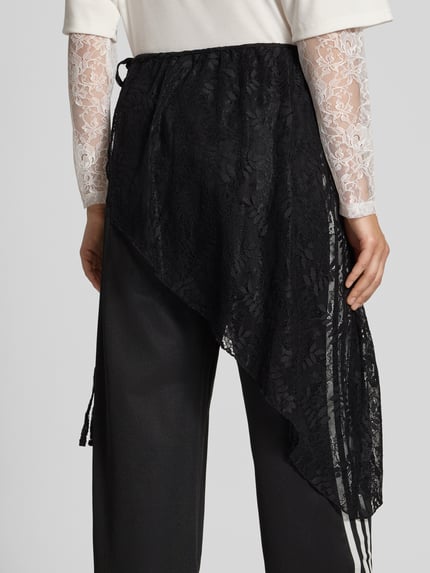 Frauenmodel trägt Loose Fit Sweathose aus Baumwoll-Mix Modell '2IN1 LACE FIREBIRD' von adidas Originals in Schwarz mit asymmetrischer Spitzenlage, Damen Sweathose, Ganzkörperansicht Rückansicht.