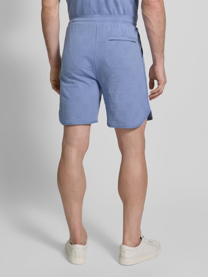 Männermodel trägt Regular Fit Shorts aus katoenmix Modell 'JT_Member Short' van BOSS Green, grafisch gestructureerd, effen blauw, elastische tailleband, zijzakken, sweatstof. Ganzkörperansicht Rückansicht.