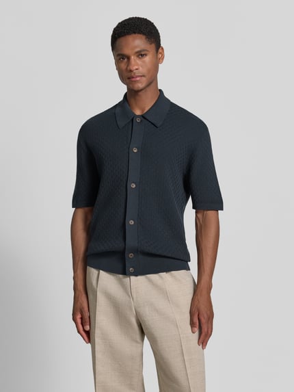 Männermodel trägt Regular Fit poloshirt met structuurpatroon model 'ARAAWEN' van Tiger Of Sweden in puur katoen met knoopsluiting, polokraag, korte mouw, ruglengte maat M 68 cm, mouwlengte 28 cm, donkerblauw, simple vormen en gladde textuur. Ganzkörperansicht van voren.