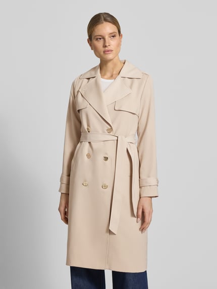 Frauenmodel trägt Zweireihiger Trenchcoat mit Bindegürtel von MICHAEL Michael Kors in Beige mit Reverskragen, Regular-Fit, Ganzkörperansicht von vorne. Rückenlänge 47 cm, Schulterbreite 40 cm, Brustweite 50 cm, Ärmellänge 63 cm, Größe S.