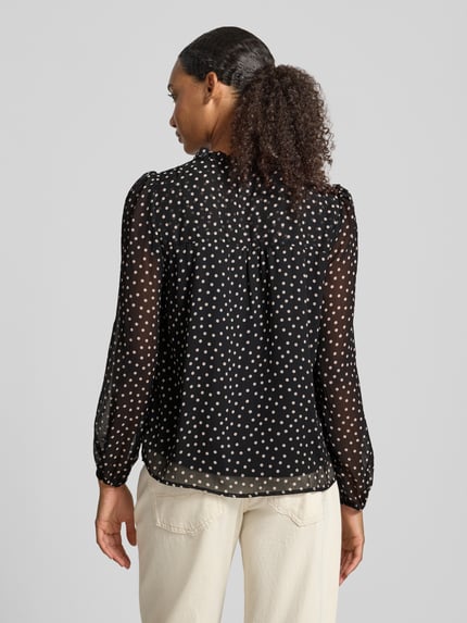 Frauenmodel trägt Regular Fit Langarmbluse mit Bindeverschluss Modell 'DITSY' von ONLY, schwarze Bluse mit weißen Punkten, Damen Langarmbluse von ONLY, Ganzkörperansicht Rückansicht.