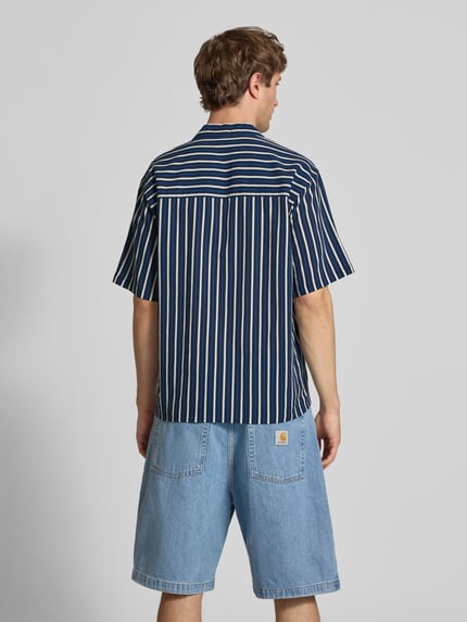 Männermodel trägt Regular Fit Freizeithemd mit Reverskragen Modell 'HOWIE' von Redefined Rebel, dunkelblau-weiß gestreift, Allover-Look, Reine Baumwolle, Label-Detail, Rückenlänge bei Größe M 60 cm, Schulterbreite 60 cm, Ärmellänge 30 cm, Ganzkörperansicht Rückansicht.