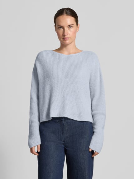 Frauenmodel trägt Oversized Wollpullover aus Alpaka-Mix von DRYKORN, mieszanka wełny z alpaki, krój oversized, okrągły dekolt, szerokie, opuszczone ramiona, efekt prążkowania, Długość tyłu w rozmiarze S: 48 cm, Długość rękawów w rozmiarze S: 70 cm, jasnoniebieski, prosta forma, miękka tekstura, Ganzkörperansicht von vorne.
