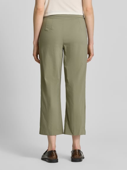 Vrouwenmodel draagt Hose aus Viskose-Mix in verkürzter Passform Modell 'FENJA2' van STEHMANN in olijfgroen, elastische tailleband, rechte pijpen, viscosemix met stretch, verkorte fit, detail van de achterkant, context: damesbroek, taillewijdte maat 36: 40 cm, binnenbeenlengte maat 36: 66 cm, volledige achteraanzicht.