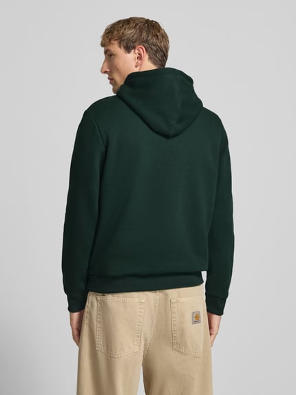 Männermodel trägt Hoodie mit Känguru-Tasche Modell 'BRADLEY' von JACK & JONES in Dunkelgrün, lockerer Schnitt, Ganzkörperansicht Rückansicht. Baumwoll-Materialmix, Kapuze mit Tunnelzug, sichtbare Struktur.