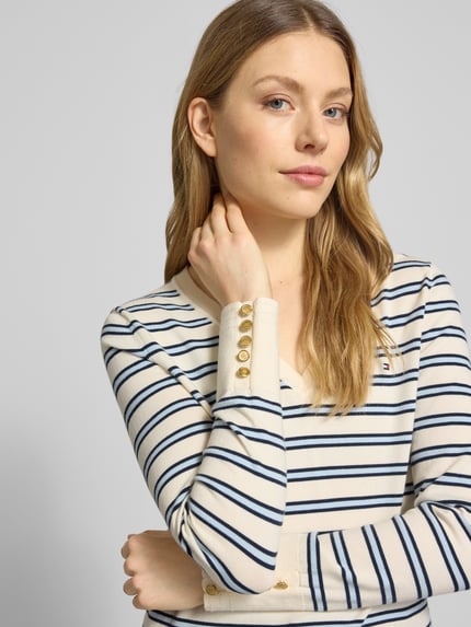 Frauenmodel trägt Regular Fit Strickpullover aus reiner Baumwolle von Tommy Hilfiger, Optik:Allover-Muster, Gestreift, V-Ausschnitt, Langarm, Ärmelabschluss: Gerippt, Zierknöpfe, Logo-Stitching, Strick, Nahaufnahme Oberkörper