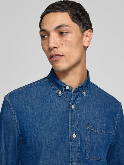 Männermodel trägt Regular Fit Jeanshemd mit Brusttasche Modell 'BROOK' von JACK & JONES aus reiner Baumwolle, Nahaufnahme Oberkörper.