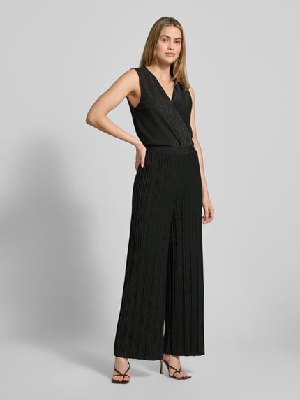 Frauenmodel trägt schimmernden Damen Jumpsuit Modell 'Li44ana' von ZABAIONE, Material-Mix mit Stretch-Anteil, Regular-Fit, V-Ausschnitt, schwarze Farbe, feine Plissee-Struktur, Ganzkörperansicht von vorne.