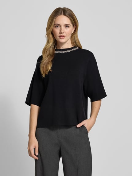 Frauenmodel trägt Strickshirt mit Ziersteinbesatz Modell 'DORISE' von ICHI, Schwarz, Viskose-Mix, Relaxed Fit, Ganzkörperansicht von vorne.