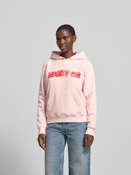 Frauenmodel trägt Oversized Hoodie aus reiner Baumwolle von Kenzo in Rosa mit Statement-Print, Känguru-Tasche, elastische Abschlüsse, Rückenlänge bei Größe S 59 cm, Ganzkörperansicht von vorne.