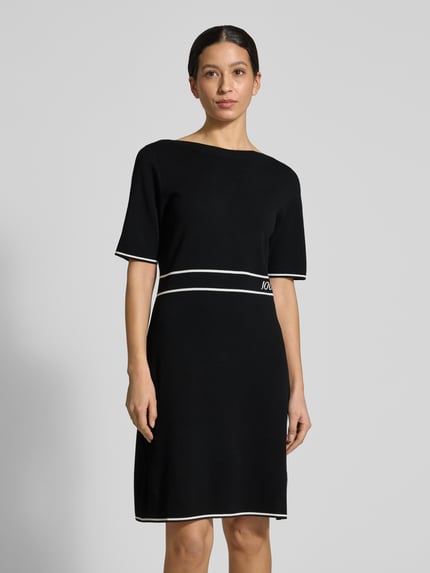 Frauenmodel trägt Regular Fit Kleid aus Viskose-Mix Modell 'Kirla' von JOOP! in Schwarz mit weißen Akzenten, Strick-Optik, Nahaufnahme Oberkörper.
