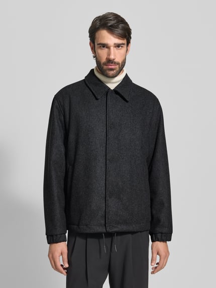 Männermodel trägt Regular Fit Kurzmantel aus Schurwoll-Mix Modell 'BAKS' von HUGO in Melange-Optik, dunkle Farbe, Ganzkörperansicht von vorne.