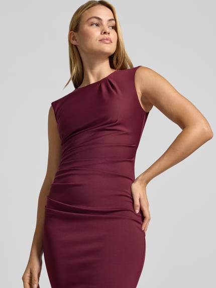 Frauenmodel trägt Cocktailkleid mit Raffungen von Rinascimento in Bordeauxrot, Material-Mix mit Stretch-Anteil, Nahaufnahme Oberkörper.