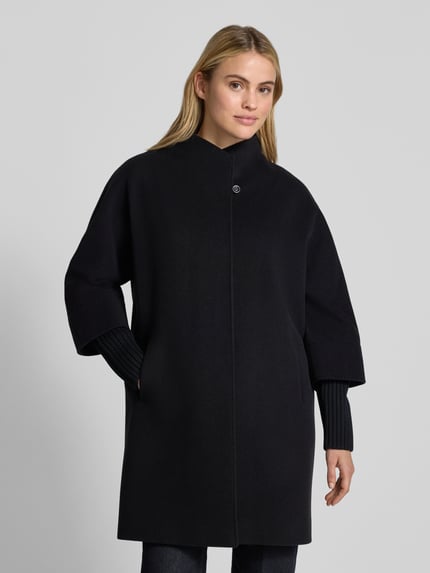 Frauenmodel trägt Jacke aus Lanawolle-Kaschmir-Mix mit herausnehmbarem Strickarm von ICONS Cinzia Rocca in Schwarz, Regular Fit, Stehkragen, Knopfverschluss, Eingrifftaschen, glatte Struktur, Ganzkörperansicht von vorne. Rückenlänge 89 cm, Schulterbreite 52 cm, Brustweite 57 cm, Ärmellänge 64 cm.
