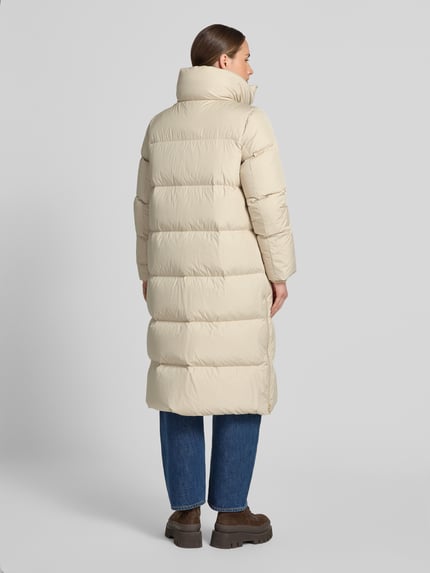 Frauenmodel trägt Regular Fit Daunenmantel mit abnehmbaren Rucksackriemen von Marc O'Polo in Beige, gesteppte Struktur, Ganzkörperansicht Rückansicht. Damen Daunenmantel von Marc O'Polo