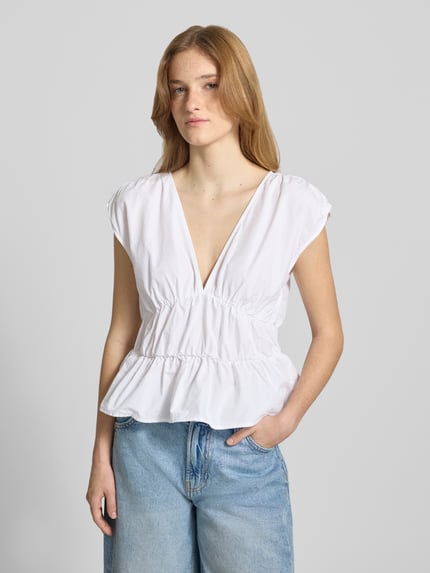 Kobiece modelka nosi Peplum Top mit V-Ausschnitt von Gina Tricot, biała bawełna, dopasowany krój, marszczenia, długość tyłu 50 cm, widok z przodu, ujęcie do pasa.