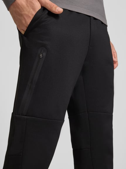 Männermodel trägt schwarze Sweatpants mit elastischem Bund Modell 'GORDON FUSION' von JACK & JONES, Material-Mix, Nahaufnahme Oberschenkel.